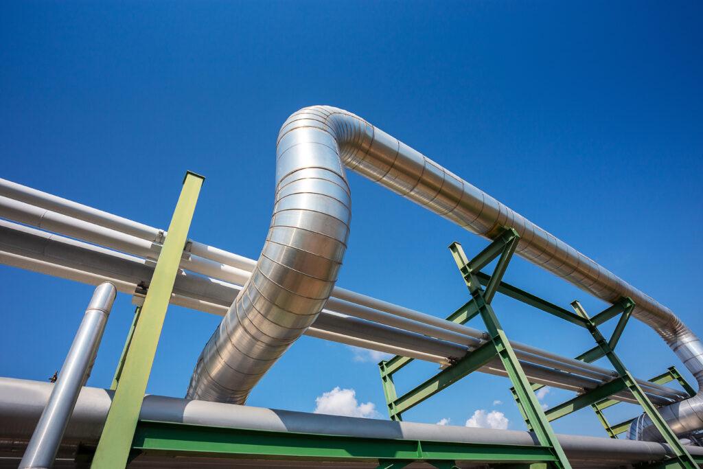 Insulation of steam pipe for steam, heat utility, transportation on rack in industrial zone with clear blue sky